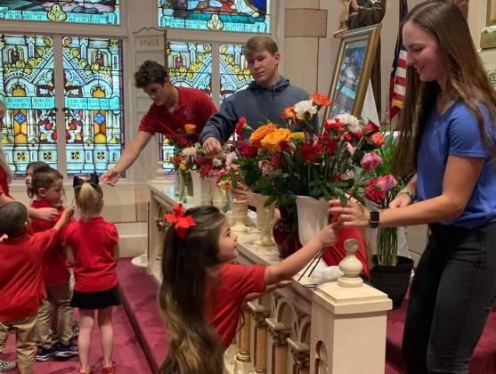 Elementary students present flowers to the high school students at Shiner Catholic School at the May crowning ceremony.