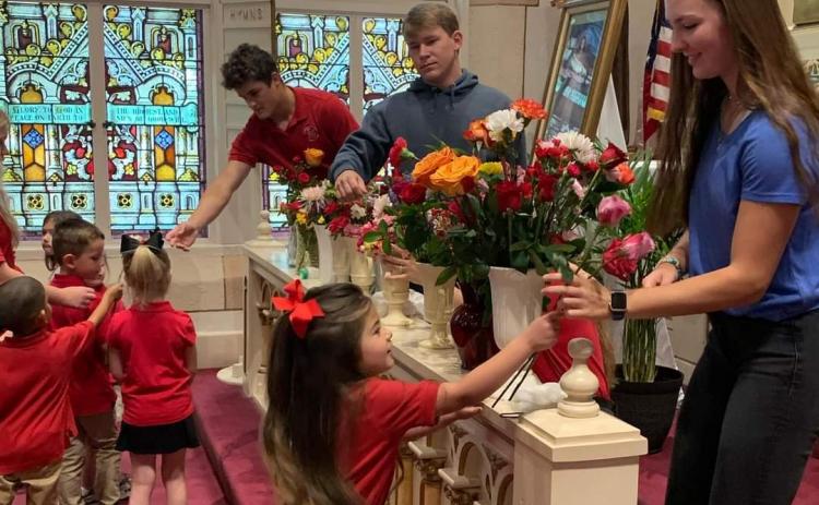 Elementary students present flowers to the high school students at Shiner Catholic School at the May crowning ceremony.
